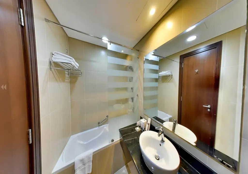 نمای دیگری از حمام اتاق Standard King Room با سینک و آینه بزرگ.